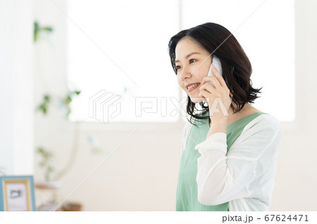 スマホで通話するミドル女性【リビング】 スマホで通話するミドル女性【リビング】 67624471