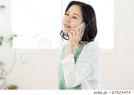 スマホで通話するミドル女性【リビング】 67624474