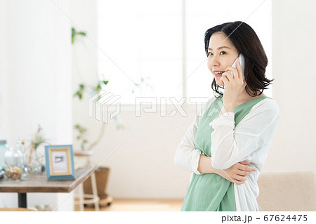 スマホで通話するミドル女性【リビング】 67624475