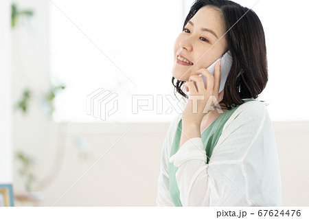スマホで通話するミドル女性【リビング】 67624476