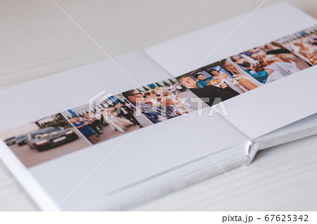 Open photobook with wrdding photo of beautiful couple on white wooden table 67625342