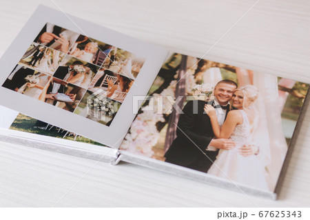 Open photobook with wrdding photo of beautiful couple on white wooden table Open photobook with wrdding photo of beautiful couple on white wooden table 67625343