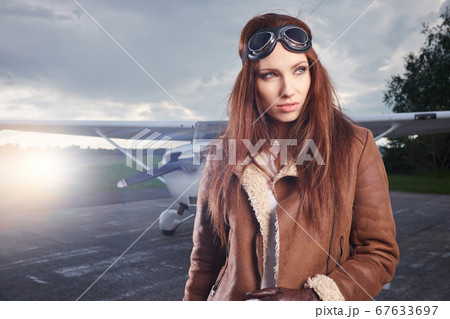 A young female pilot is standing next to a small A young female pilot is standing next to a small 67633697