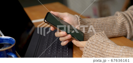 Female hands holding smartphone while sitting at Female hands holding smartphone while sitting at 67636161