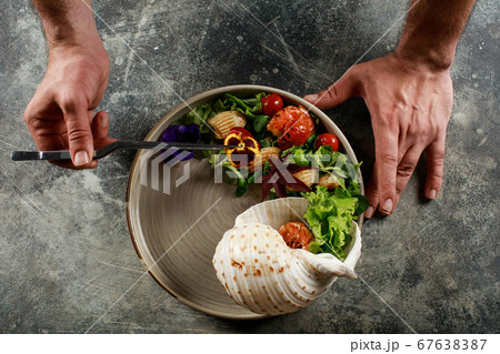 The chef prepares a salad of seafood and vegetables. 67638387