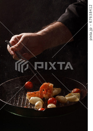 Chef cooks seafood, shrimp in a pan with vegetables. 67638412