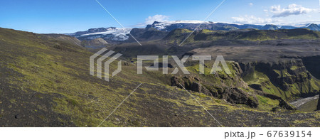 Panoramic landscape with blue Markarfljot river canyon, green hills and eyjafjallajokull volcano glacier. Laugavegur hiking trail. Fjallabak Nature Reserve, Iceland. Summer blue sky 67639154