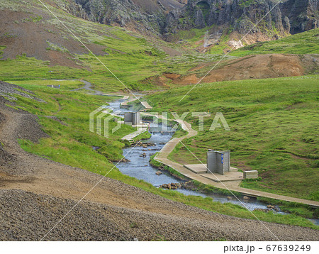 Natural geothermal bath in a Hot River stream in Reykjadalur Valley with wooden footpath and changing rooms. South Iceland near Hveragerdi city. Summer sunny morning 67639249