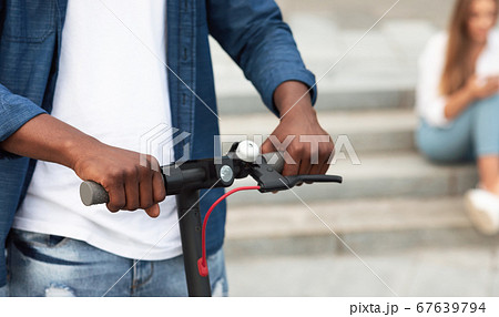 Black man holding handle of a stand-up scooter Black man holding handle of a stand-up scooter 67639794