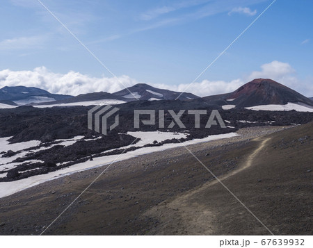 Red and black volcanic Iceland landscape at Fimmvorduhals hiking trail with glacier volcano lava field, snow and magni and mudi hill, createed by eruption of Eyjafjallajokull in 2010 which affected 67639932
