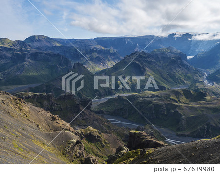 Landscape of Godland and thorsmork with rugged green moss covered rocks and hills, bending river canyon, Iceland, Fimmvorduhals hiking trail. Summer blue sky white clouds Landscape of Godland and thorsmork with rugged green moss covered rocks and hills, bending river canyon, Iceland, Fimmvorduhals hiking trail. Summer blue sky white clouds 67639980