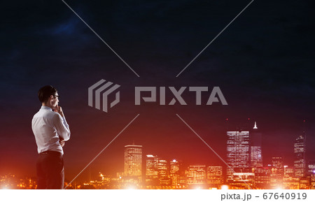 Businessman viewing night glowing city Businessman viewing night glowing city 67640919