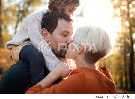 Young couple with small daughter on a walk in autumn forest, kissing. Young couple with small daughter on a walk in autumn forest, kissing. 67642260