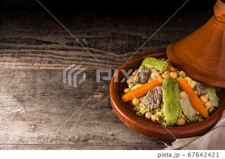 Traditional tajine with vegetables, chickpeas, meat and couscous on wooden table Traditional tajine with vegetables, chickpeas, meat and couscous on wooden table 67642421