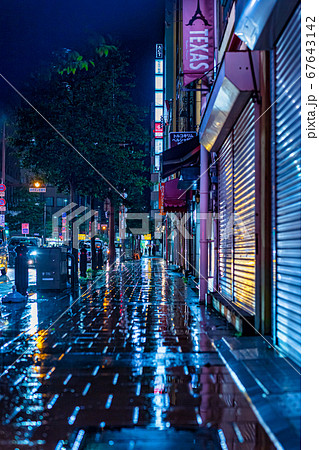 街の光が反射して綺麗な雨に濡れた都市の歩道の写真素材