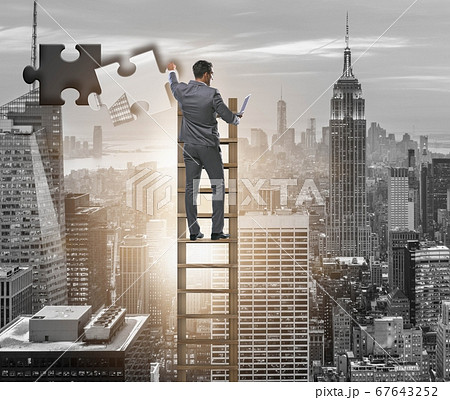 Businessman putting together jigsaw puzzle pieces Businessman putting together jigsaw puzzle pieces 67643252