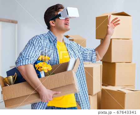 Young man wearing VR glasses moving in new apartment 67643341