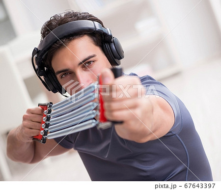 Man doing sports with resistance band and listening to music 67643397