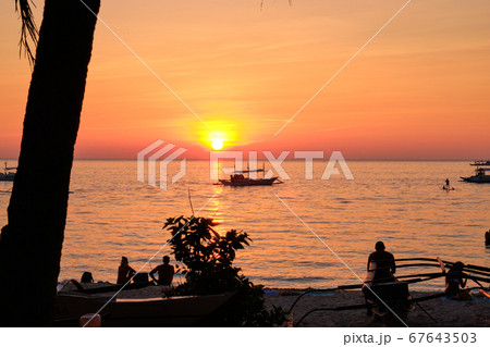 Boracay, Philippines - Jan 27, 2020: Sunset on Boracay island. Sailing and other traditional boats with tourists on the sea against the background of the setting sun. Tourists are sitting on the beach 67643503