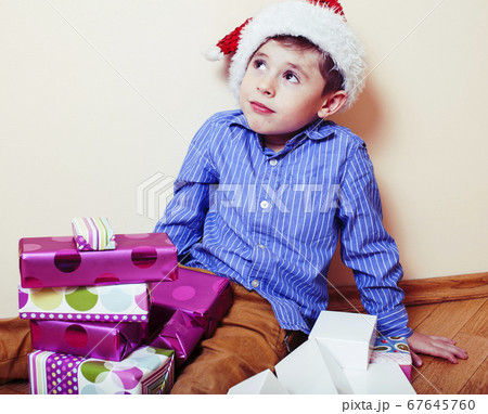 little cute boy with Christmas gifts at home wearing red Santas hat. closeup emotional happy smiling in mess with toys, lifestyle holiday people concept little cute boy with Christmas gifts at home wearing red Santas hat. closeup emotional happy smiling in mess with toys, lifestyle holiday people concept 67645760