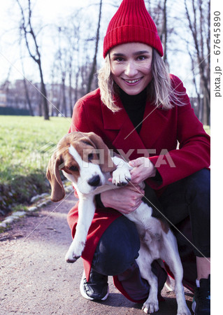 pretty young girl in redd coat playing with dog outside in green park, lifestyle people concept pretty young girl in redd coat playing with dog outside in green park, lifestyle people concept 67645890