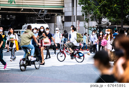 日本の東京都市景観 渋谷のスクランブル交差点の危険運転自転車 マスク姿 奥は渋谷駅方向 の写真素材