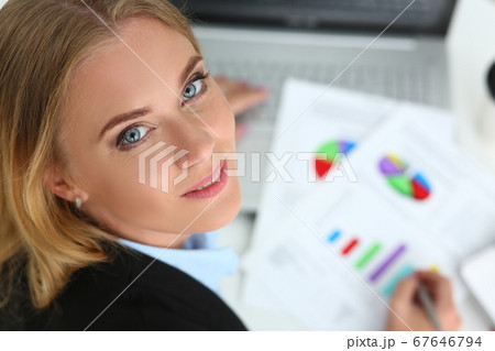 Smiling businesswoman studying financial charts at work 67646794