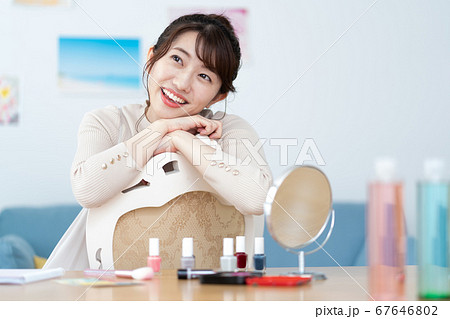 自宅のリビングでカメラ目線で微笑む若い女性のポートレート 67646802