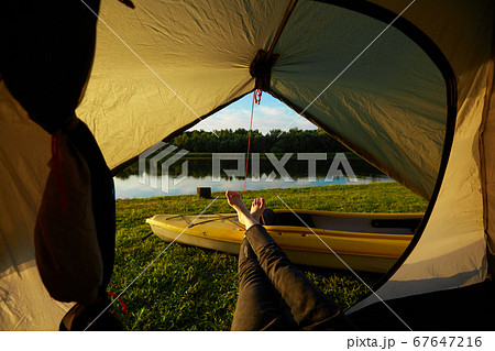 Feet of young women relaxing with lake view from tent camping entrance outdoor. Travel wanderlust lifestyle concept adventure vacations outdoor, Summer holiday and vacation trip 67647216