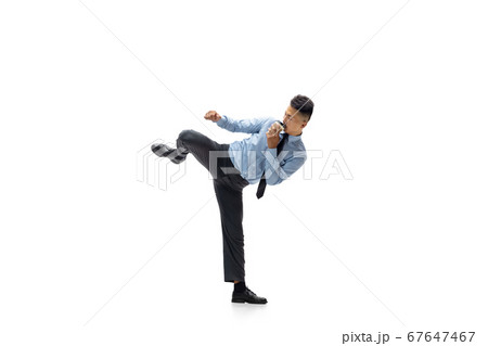 Man in office clothes practicing taekwondo on white background. Unusual look for businessman in motion, action. Sport, healthy lifestyle. Man in office clothes practicing taekwondo on white background. Unusual look for businessman in motion, action. Sport, healthy lifestyle. 67647467