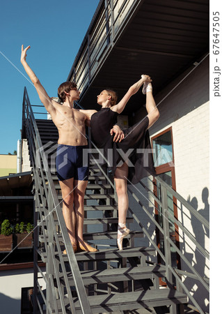 Couple of modern ballet dancers performing on the stairs at the city Couple of modern ballet dancers performing on the stairs at the city 67647505