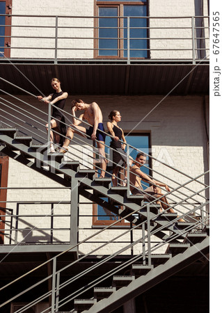 The group of modern ballet dancers performing on the stairs at the city 67647565