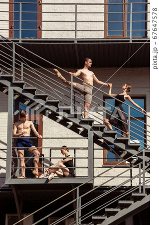 The group of modern ballet dancers performing on the stairs at the city The group of modern ballet dancers performing on the stairs at the city 67647578