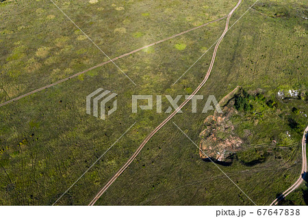 The view from the top, like a dirt unpaved roads cross the meadow. Shot on drone.  67647838