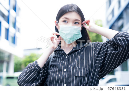 フェースマスクを外そうとしている若い女性 フェースマスクを外そうとしている若い女性 67648381