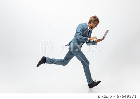 Man in office clothes running, jogging on white background. Unusual look for businessman in motion, action. Sport, healthy lifestyle. Man in office clothes running, jogging on white background. Unusual look for businessman in motion, action. Sport, healthy lifestyle. 67649571
