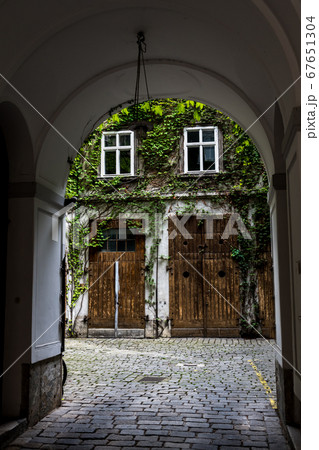 Courtyard Of A HIstoric Building With Wooden Doors And Ivy Overgrown Walls Courtyard Of A HIstoric Building With Wooden Doors And Ivy Overgrown Walls 67651304