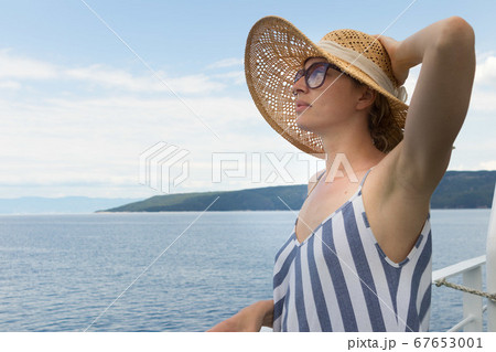 Beautiful, romantic blonde woman taking selfie self portrait photo on summer vacations traveling by cruse ship ferry boat. 67653001