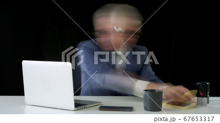 Stressed businessman works furiously in the office 67653317