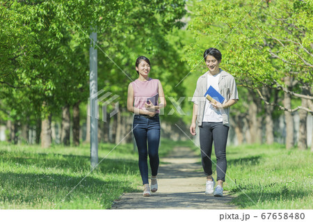 会話をしながら歩く若者2人組 67658480
