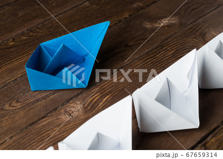 Business leadership concept with white and color paper boats on wooden table Business leadership concept with white and color paper boats on wooden table 67659314