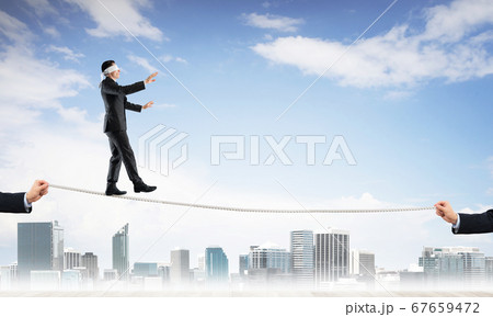 Business concept of risk support and assistance with man balancing on rope 67659472
