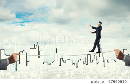 Business concept of risk support and assistance with man balancing on rope 67660650
