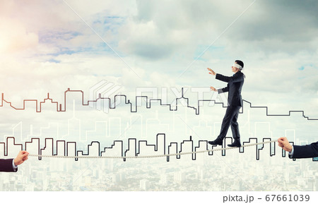 Business concept of risk support and assistance with man balancing on rope 67661039