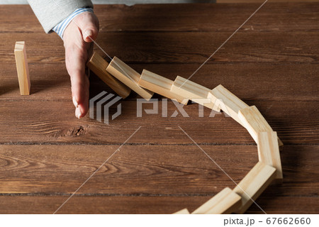 Businesswoman protecting dominoes from falling Businesswoman protecting dominoes from falling 67662660
