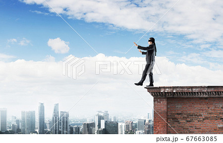 Danger and risk concept with businessman making step from edge Danger and risk concept with businessman making step from edge 67663085