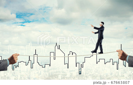 Business concept of risk support and assistance with man balancing on rope 67663807