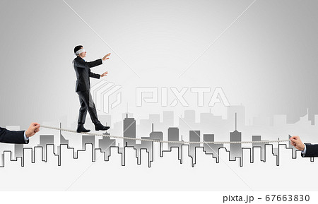 Business concept of risk support and assistance with man balancing on rope 67663830
