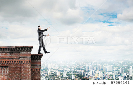 Danger and risk concept with businessman making step from edge Danger and risk concept with businessman making step from edge 67664141