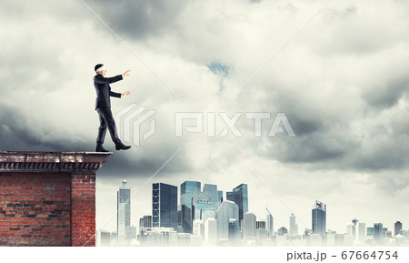 Danger and risk concept with businessman making step from edge Danger and risk concept with businessman making step from edge 67664754